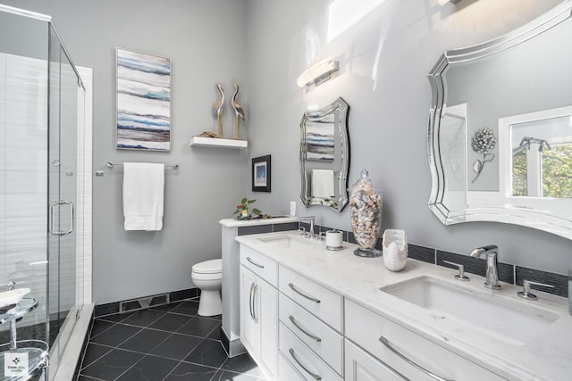 bathroom featuring toilet, a stall shower, and a sink