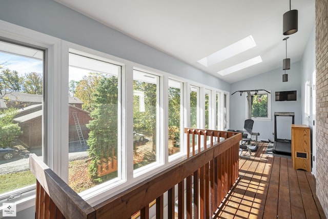 sunroom / solarium featuring hardwood / wood-style floors and vaulted ceiling with skylight