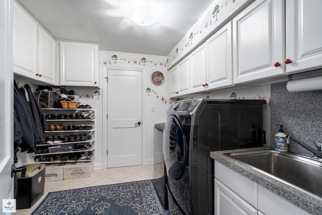 washroom with light tile patterned floors, a sink, cabinet space, and washing machine and clothes dryer