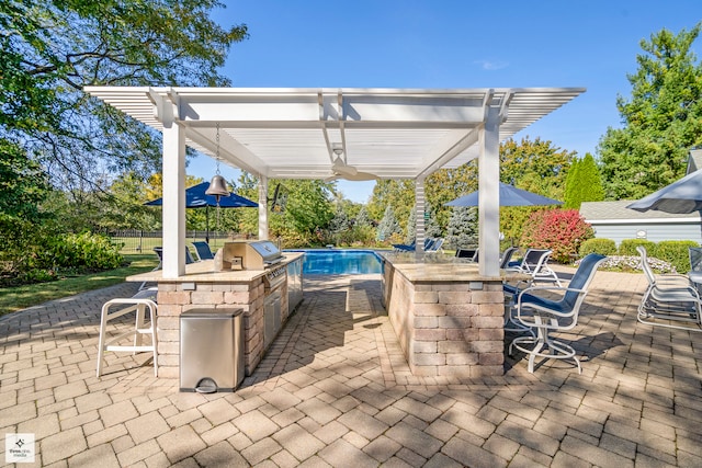 view of patio / terrace featuring an outdoor kitchen, exterior bar, a fenced in pool, and a pergola