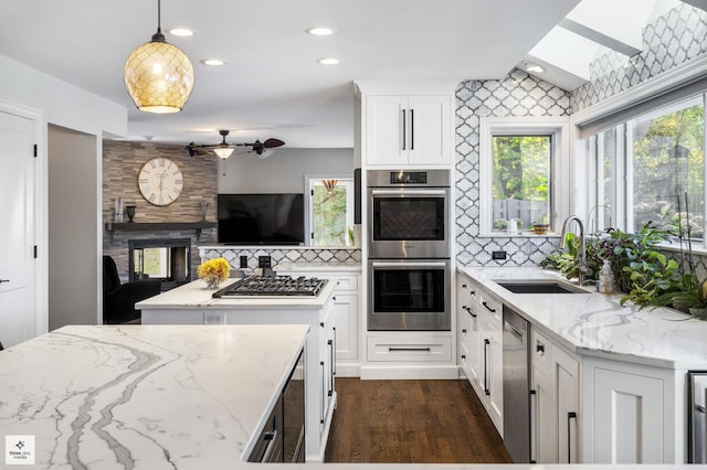 kitchen featuring dark wood-style floors, backsplash, appliances with stainless steel finishes, and a sink