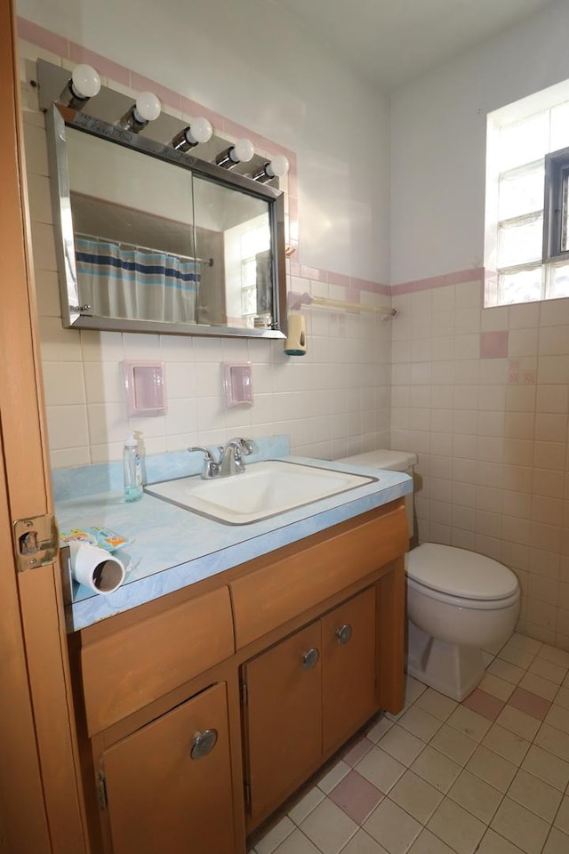 bathroom featuring tile patterned flooring, vanity, tile walls, and toilet