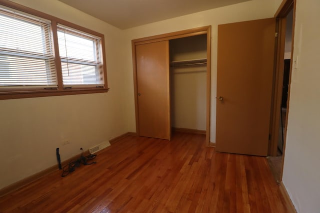 unfurnished bedroom with dark wood-type flooring and a closet