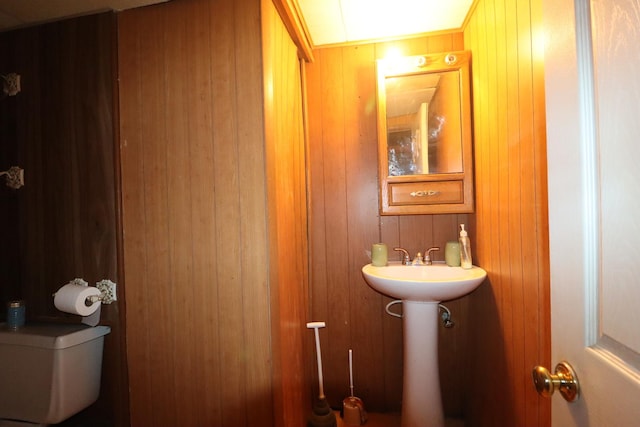 bathroom featuring wood walls and toilet