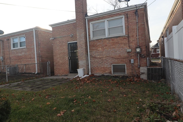 rear view of house featuring central air condition unit and a yard