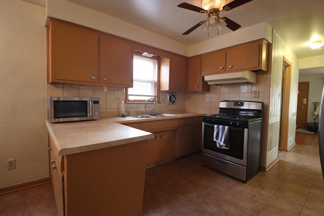 kitchen featuring sink, ceiling fan, light tile patterned floors, appliances with stainless steel finishes, and kitchen peninsula