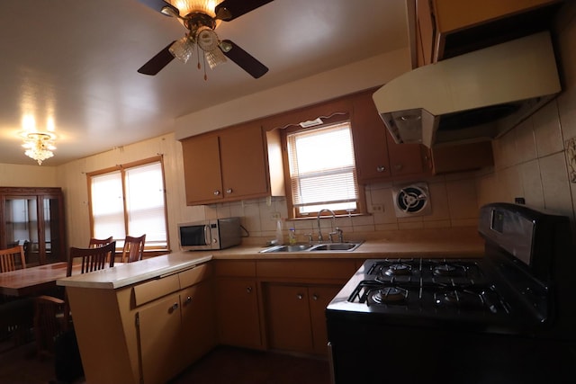 kitchen featuring kitchen peninsula, decorative backsplash, black range oven, extractor fan, and sink