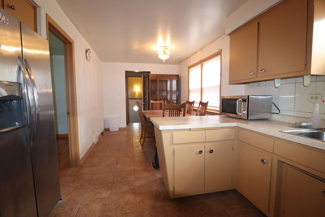 kitchen with sink, stainless steel appliances, backsplash, kitchen peninsula, and tile patterned floors