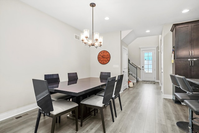 dining area with light wood-type flooring and a notable chandelier