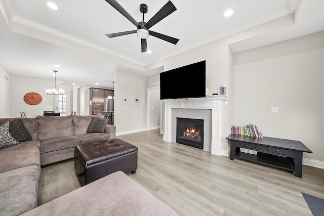 living room featuring ceiling fan with notable chandelier, light hardwood / wood-style flooring, and crown molding