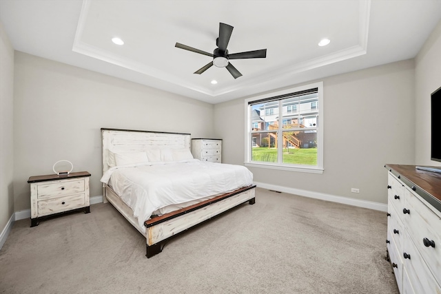 bedroom featuring ceiling fan, light carpet, and a tray ceiling