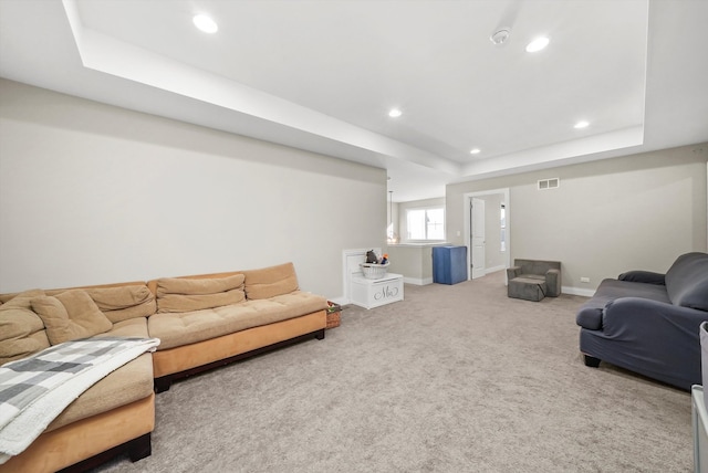 living room featuring carpet flooring and a tray ceiling