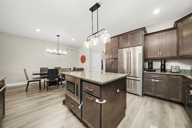 kitchen with dark brown cabinets, appliances with stainless steel finishes, hanging light fixtures, and light hardwood / wood-style flooring