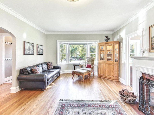 living room with ornamental molding, a brick fireplace, and light wood-type flooring