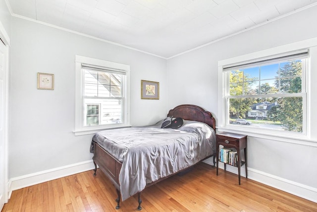 bedroom with ornamental molding, multiple windows, and hardwood / wood-style floors