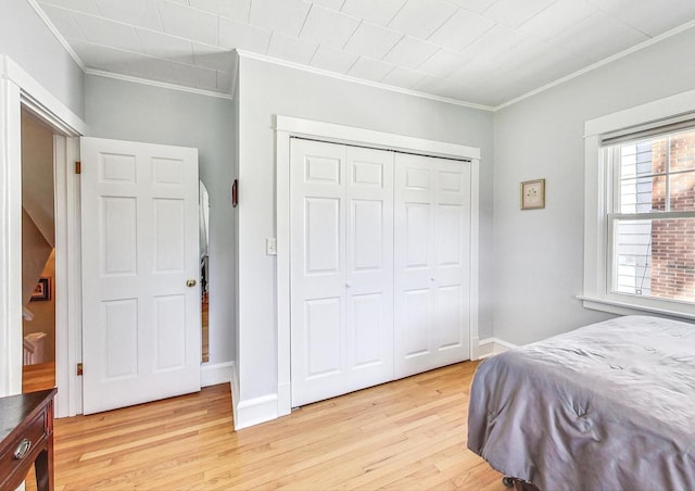 bedroom featuring light hardwood / wood-style floors, a closet, and crown molding