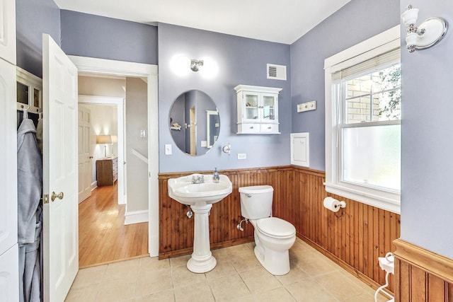 bathroom featuring wood walls, toilet, and tile patterned flooring