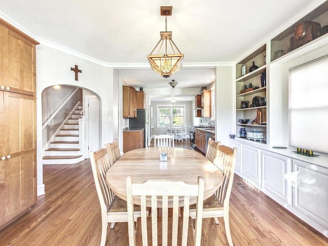 dining room with a notable chandelier, ornamental molding, and wood-type flooring