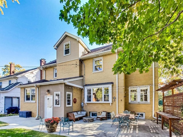 back of house featuring an outdoor living space with a fire pit and a patio area