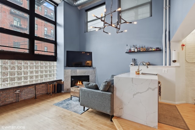 living room with a towering ceiling, a fireplace, and light wood-type flooring