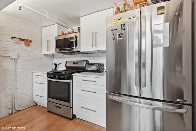 1601 S Michigan Ave Unit 108, Chicago, IL 60616 - kitchen featuring white cabinets, appliances with stainless steel finishes, light wood-style floors, light countertops, and brick wall