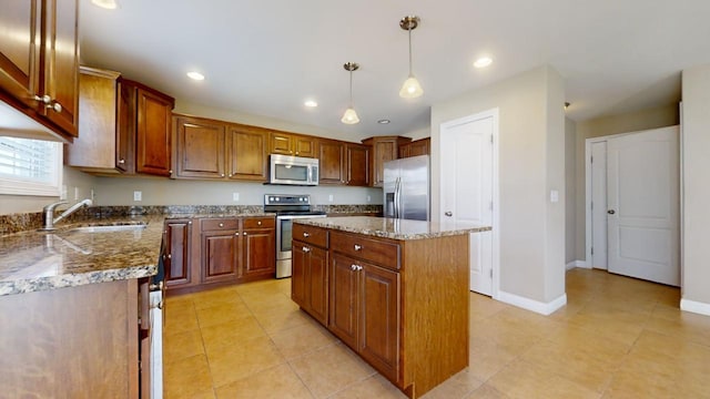 kitchen with sink, stone countertops, a center island, hanging light fixtures, and stainless steel appliances