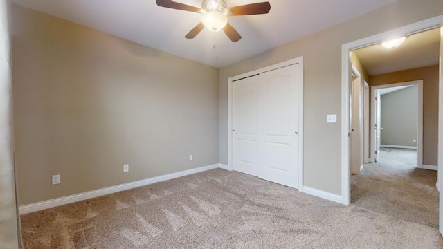 unfurnished bedroom featuring light colored carpet, a closet, and ceiling fan