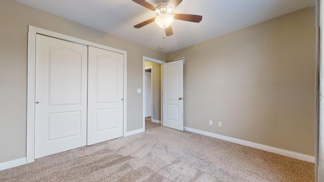 unfurnished bedroom featuring ceiling fan, light carpet, and a closet