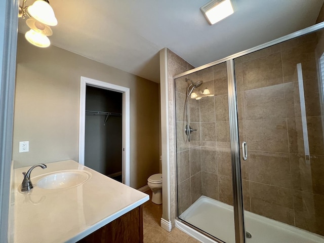 bathroom with vanity, a shower with shower door, tile patterned floors, and toilet