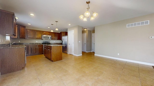 kitchen with sink, an inviting chandelier, a kitchen island, pendant lighting, and stainless steel appliances