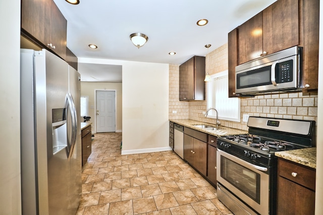 kitchen with appliances with stainless steel finishes, decorative backsplash, light stone countertops, and sink