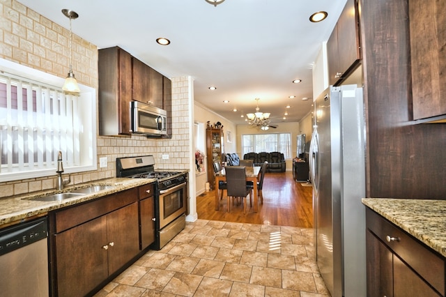 kitchen featuring tasteful backsplash, sink, stainless steel appliances, decorative light fixtures, and crown molding