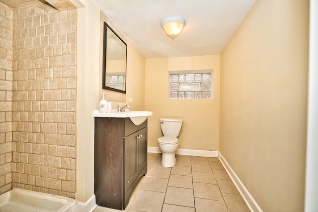 bathroom featuring vanity, a tile shower, toilet, and tile patterned floors