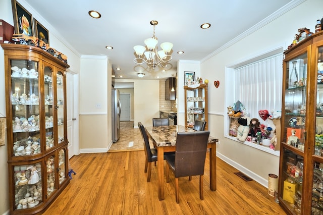 dining area with crown molding, a notable chandelier, and wood-type flooring