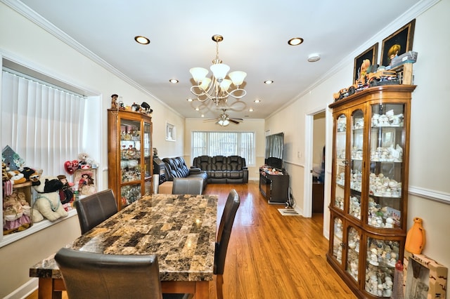 dining area with ornamental molding, ceiling fan with notable chandelier, and light hardwood / wood-style floors