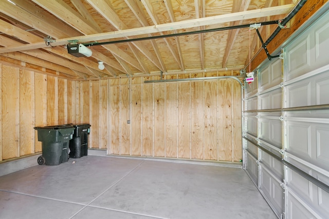 garage featuring a garage door opener and wooden walls