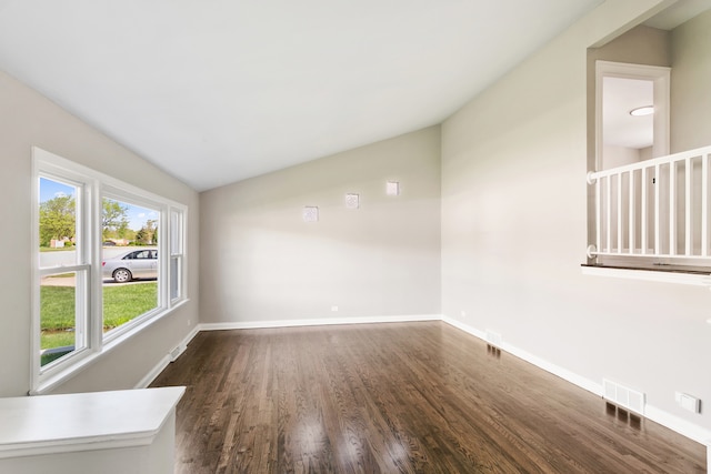 spare room featuring lofted ceiling and dark hardwood / wood-style floors