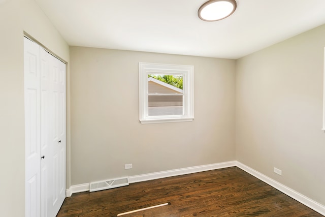 unfurnished bedroom with dark wood-type flooring and a closet