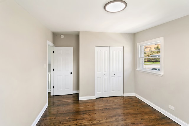 unfurnished bedroom featuring a closet and dark wood-type flooring