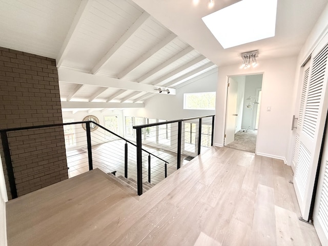 hall with lofted ceiling with skylight and light hardwood / wood-style floors