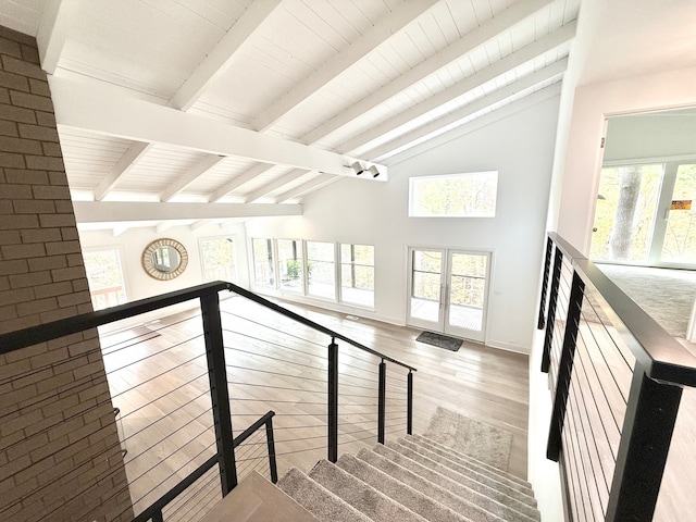 staircase with vaulted ceiling with beams, wood-type flooring, and plenty of natural light