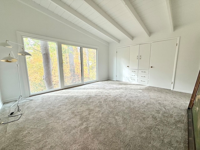 unfurnished bedroom featuring a closet, lofted ceiling with beams, and carpet flooring