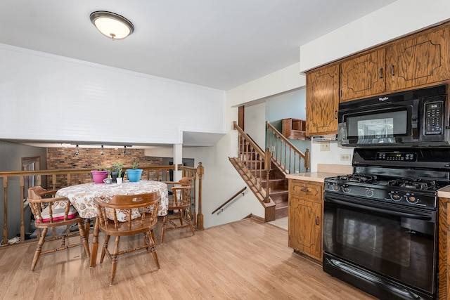 kitchen featuring black appliances, crown molding, and light wood-type flooring