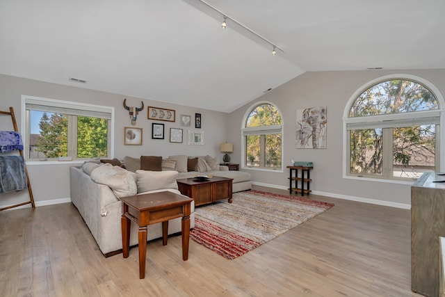 living room with vaulted ceiling, rail lighting, and light hardwood / wood-style floors