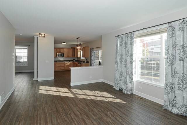 unfurnished living room with dark wood-type flooring and a wealth of natural light