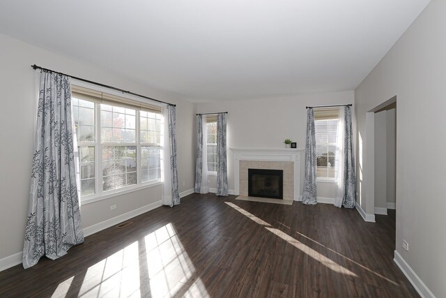 unfurnished living room featuring a tile fireplace and dark hardwood / wood-style floors