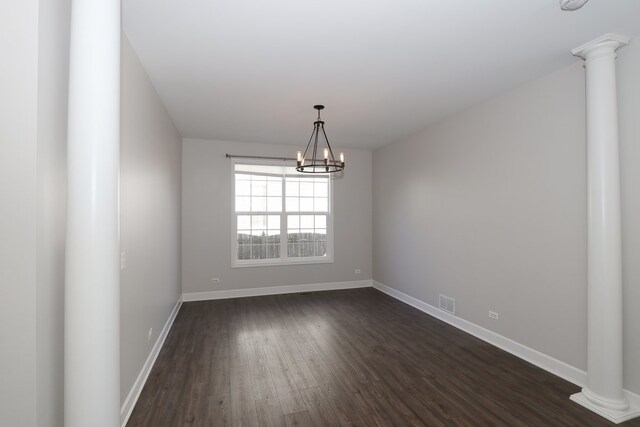 empty room featuring ornate columns, dark hardwood / wood-style flooring, and an inviting chandelier