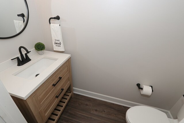 bathroom with toilet, vanity, and wood-type flooring