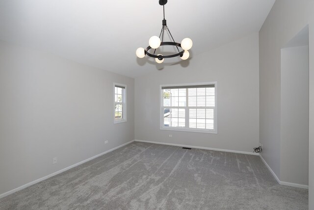 carpeted empty room featuring an inviting chandelier and vaulted ceiling