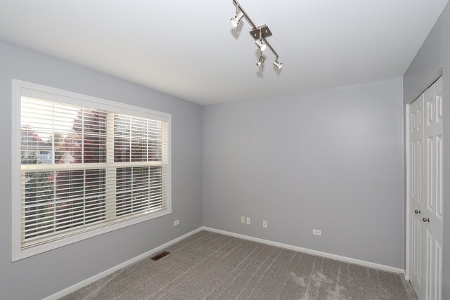 spare room featuring carpet flooring and rail lighting